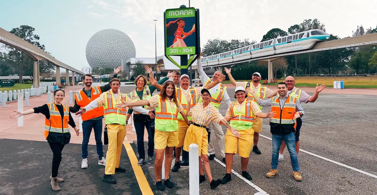 Epcot parking lot cast members and Imagineers pose with a new Moana sign.