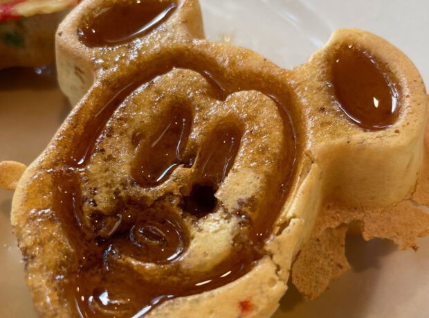 Close-up on mini Mickey Waffle covered in syrup.