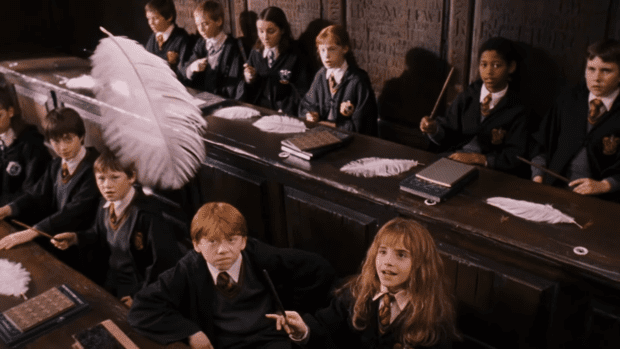 Hermione Granger happily making a feather float while Ron Weasley grimaces