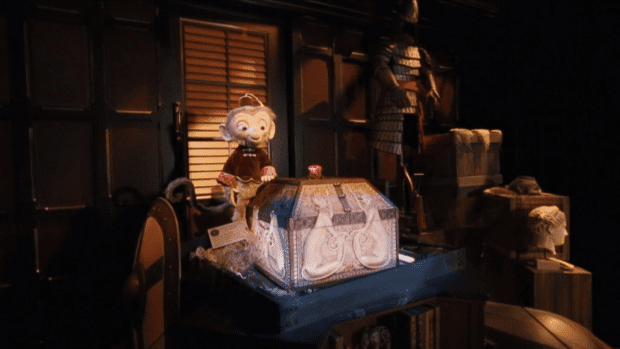 Animatronic monkey in a red suit smiling at a treasure chest