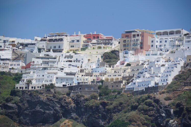 A view of white buildings cliffside in Greece.