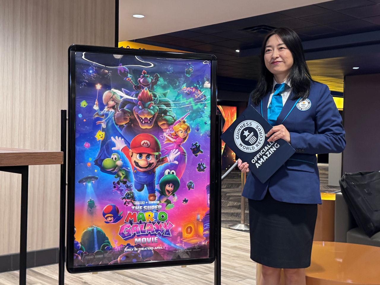 Guinness World Record representative
stands next to Super Mario Galaxy movie poster