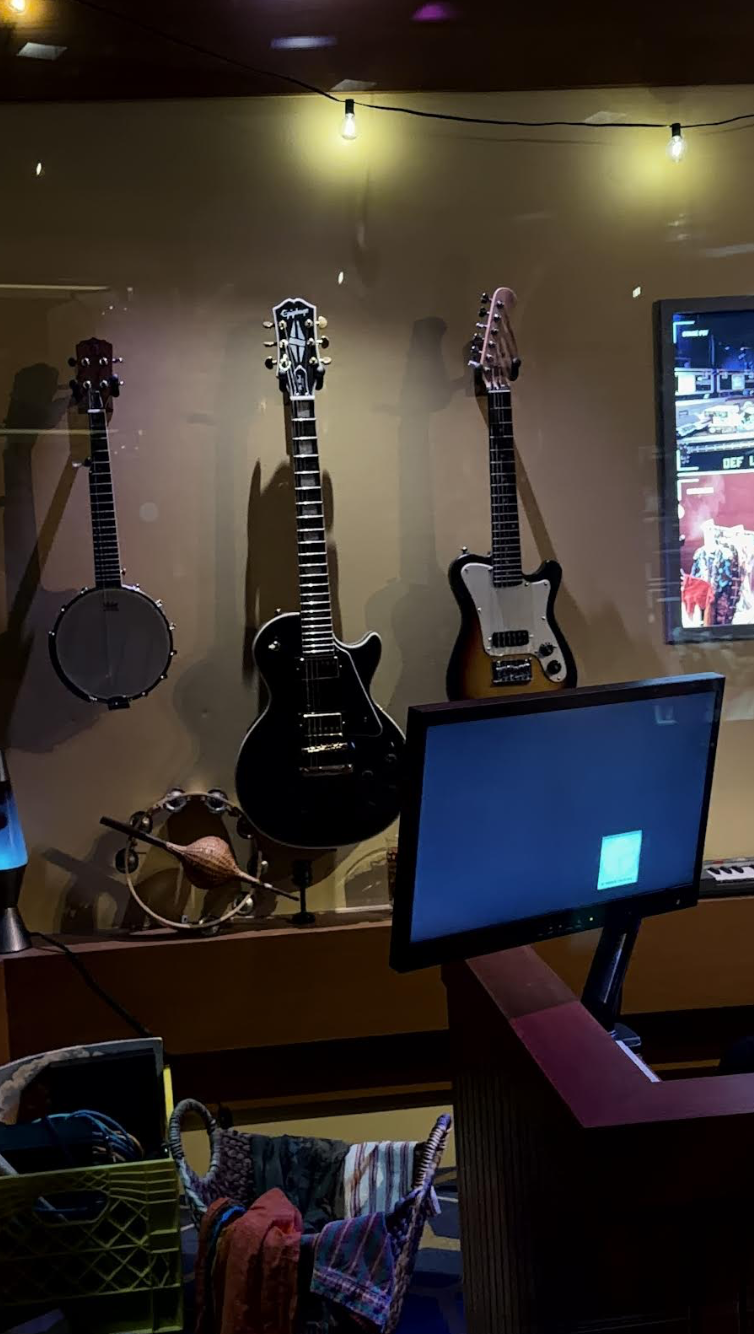 Black Les Paul guitar on wall in Muppets pre-show area behind glass