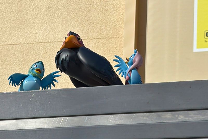 Cinderella birds and Maleficent raven figures atop directional sign at Animation Courtyard 