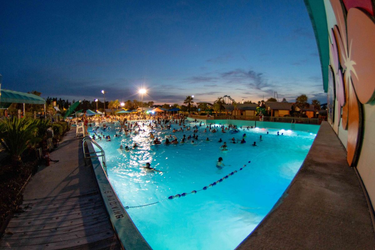 Crowded wave pool lit up at night during a Splash Island Nights event, showcasing a popular Wild Adventures summer deal feature.