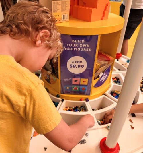 boy building lego pieces at Build Your Own Minifig at Lego Store Disney Springs
