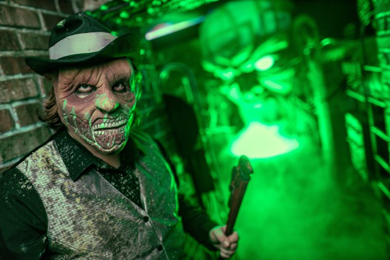 scary performer in a green line hallway for knott's scary farm halloween event