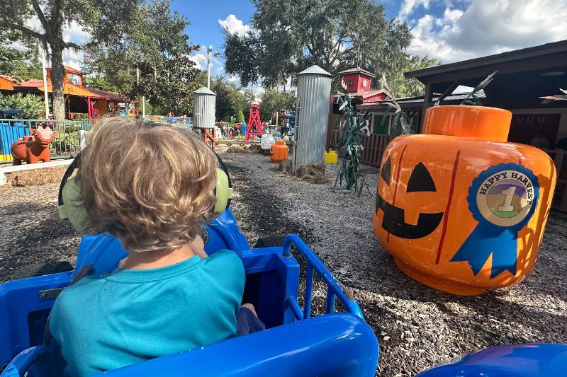 boy rides tractor ride at legoland florida with fall decorations