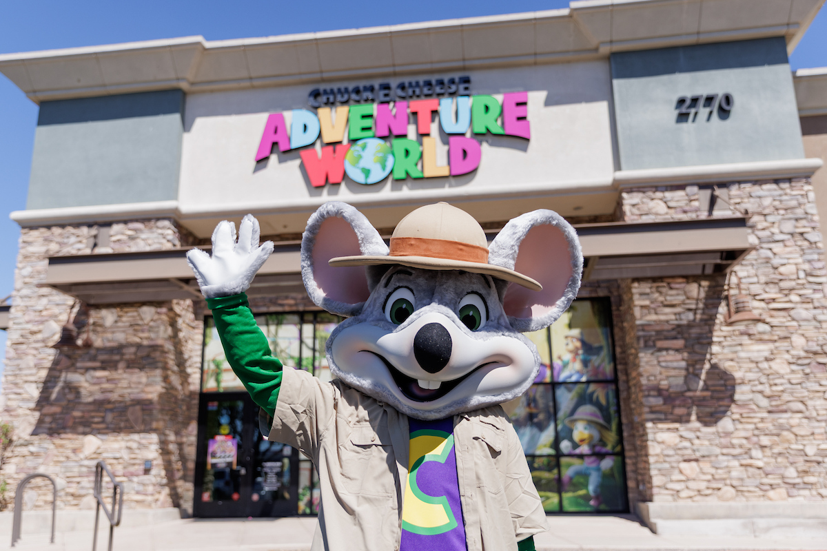Safari Chuck E. Cheese waving in front of an Adventure World expansion