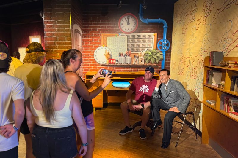 Man sits next to Walt Disney figure at Madame Tussauds Orlando
