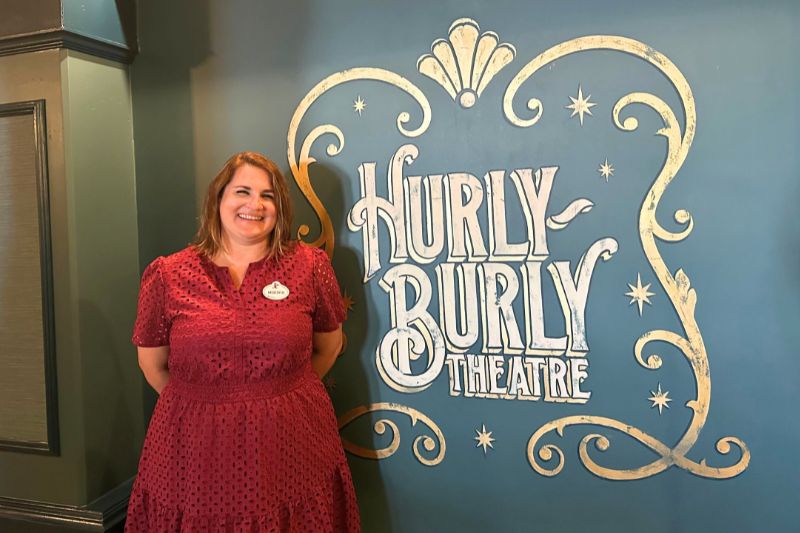 Meredith Head Senior Creative Director Walt Disney Imagineering poses next to Hurly-Burly Theatre sign