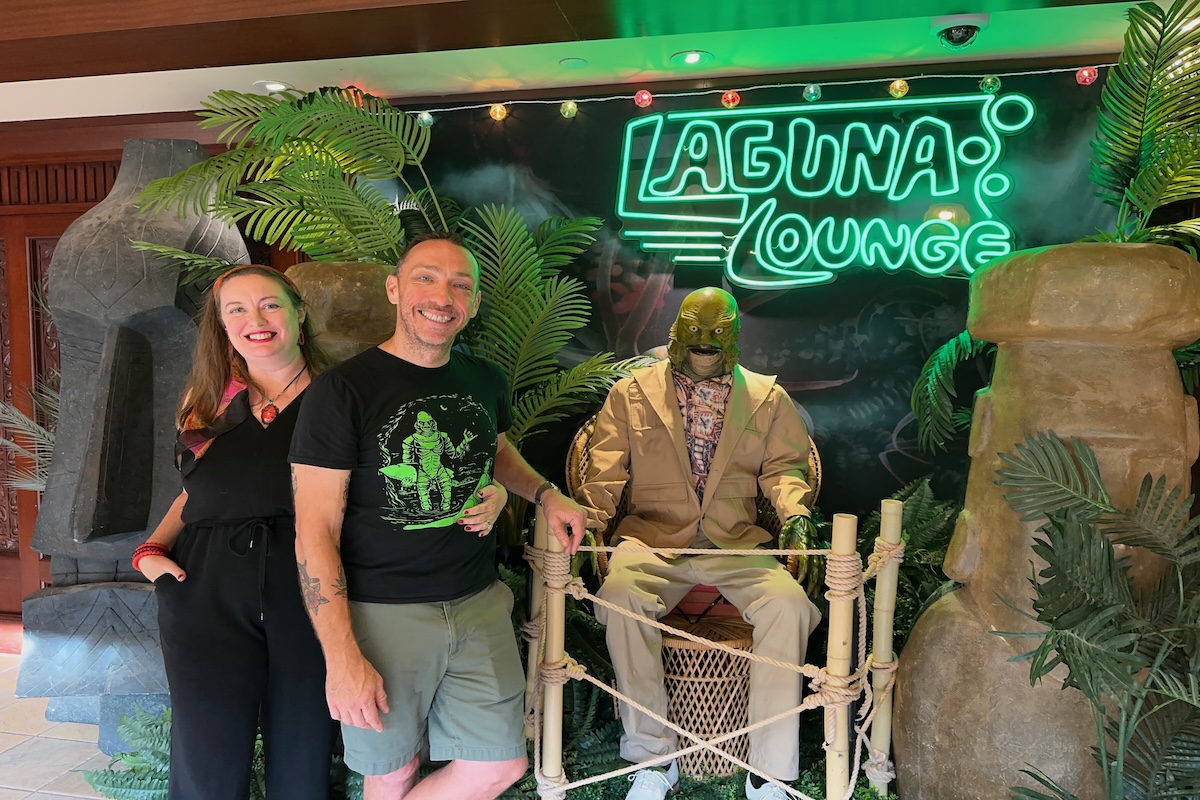 Dani Meyering poses with husband at Laguna Lounge neon sign with The Creature from the Black Lagoon