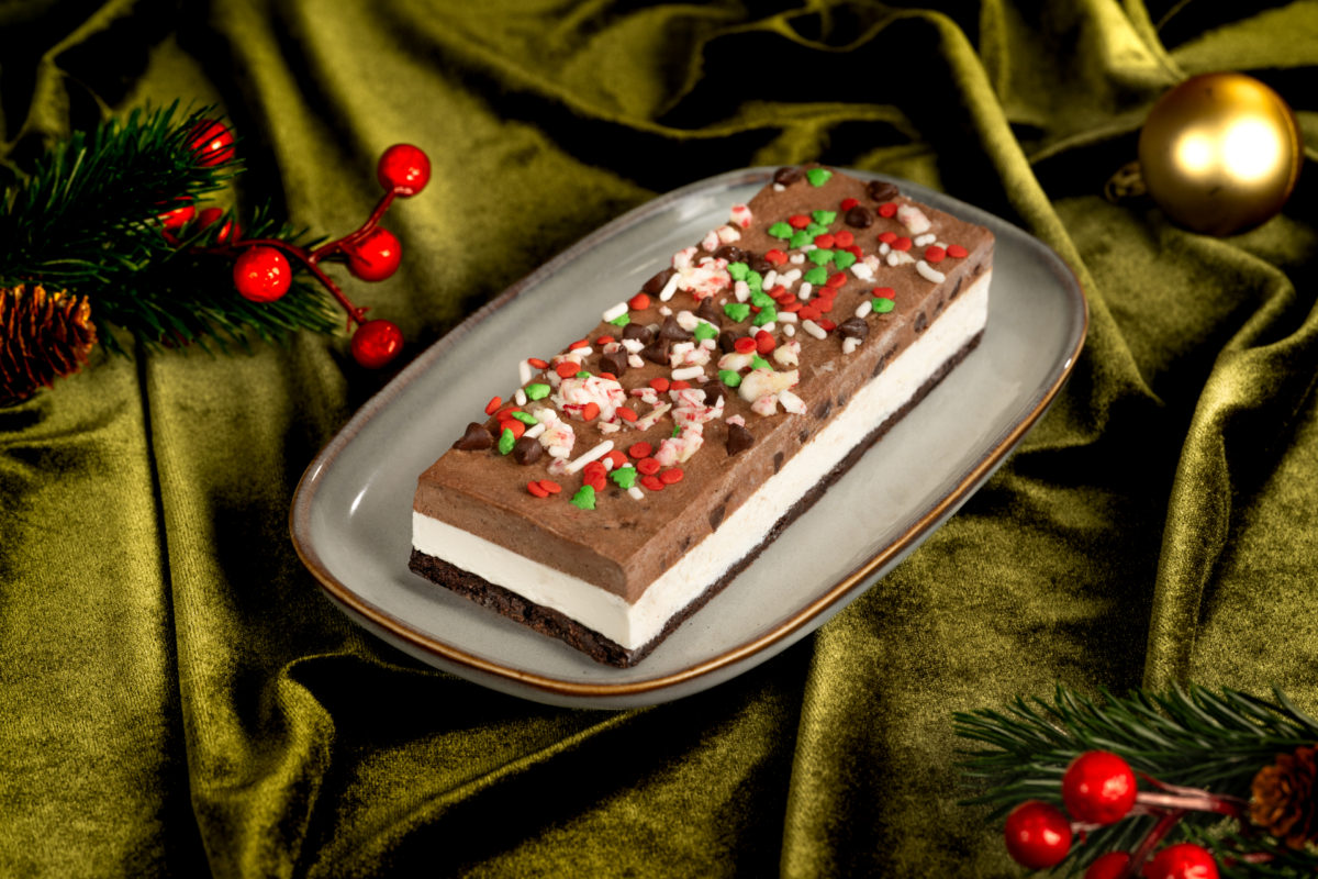 Peppermint cookie dough ice cream sandwich slice topped with red and green sprinkles, chocolate chips, and crushed peppermint